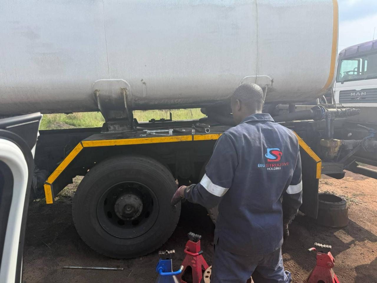 Technician maintaining a tanker truck on site